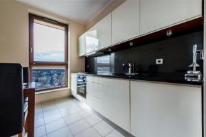 グディニャにあるMW Apartamenty - Sea Towersの白いキャビネットと大きな窓付きのキッチン