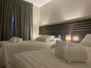 Dos camas en una habitación de hotel con sábanas blancas. en Achalay Colonia Dora Hotel Boutique, en Colonia Dora 48 fotos más