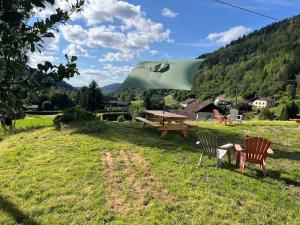 a picnic table and chairs with a green umbrella at Naturel loft 5 personnes et jardin in Saint-Maurice-sur-Moselle