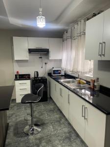 een keuken met witte kasten en een stoel erin bij Cadami apartments in Mazabuka