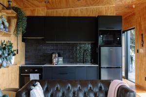 a kitchen with black appliances and a leather couch at Foudre Suite with Hot Tub at Barrelled Wines Raglan in Raglan