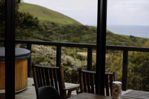 a table and chairs on a balcony with a view at Foudre Suite with Hot Tub at Barrelled Wines Raglan in Raglan