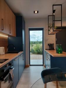 a kitchen with blue cabinets and a sliding glass door at Domki Miłe Chwile in Lubiatowo +33 photos