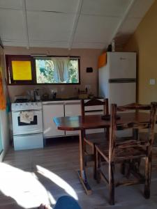 een keuken met een houten tafel en een koelkast bij Cabaña El Búho, Lago Puelo in Lago Puelo