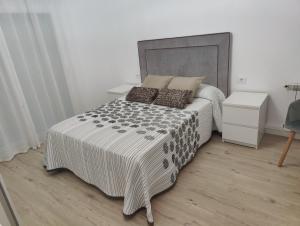 a bedroom with a large bed with a gray headboard at Ático espacioso en zona céntrica in Sarria
