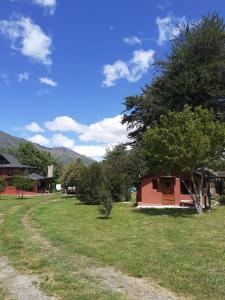 een huis in een veld met een boom bij Cabaña El Búho, Lago Puelo in Lago Puelo