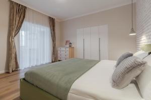 a bedroom with a large white bed and a window at Maison Jardin in Oradea