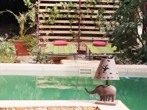 a pool with two tables and a cat statue next to it at Campement Baobab chambres d'hotes 15mn de l'aeroport in Poponguine