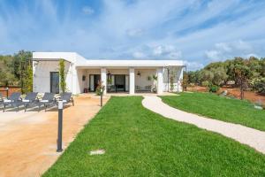 a white building with chairs and a lawn at Tenuta Buganvillea -Private pool in Ostuni