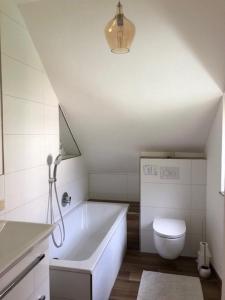 a bathroom with a white tub and a toilet at Pretty half-timbered cottage on romantic yard in Fuldabrück +22 photos