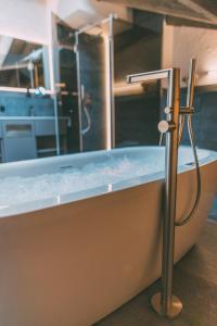 a bath tub with a shower in a room at LIVALPIN Residence - with private Sauna & Whirlpool in Garmisch-Partenkirchen