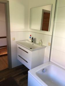 a white bathroom with a sink and a mirror at Pretty half-timbered cottage on romantic yard in Fuldabrück