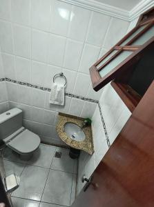 a small bathroom with a toilet and a sink at Casa Da Praça Independência in Arraial do Cabo +3 photos