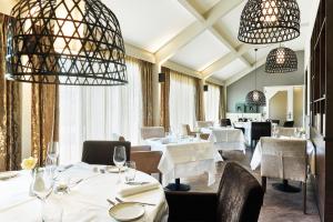 een restaurant met witte tafels en stoelen en kroonluchters bij Hotel ten Cate Emmen in Emmen