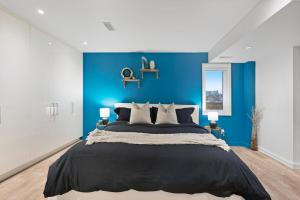 a bedroom with a blue wall and a large bed at Central and Luxury 2BR Suite with Den & BBQ, Sleeps 6! in St. Catharines