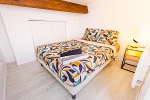 a bedroom with a bed with a colorful comforter at Appartement Jelyad Terres Fortes 3 à 10 minutes de Disney in Chanteloup-en-Brie