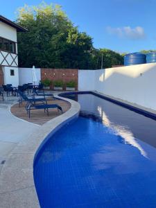 a swimming pool with chairs and a table next to a building at Recanto Brisas de Imbassaí Village C18 in Mata de Sao Joao