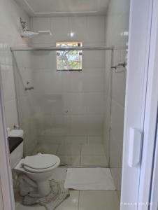 a white bathroom with a toilet and a shower at Kitnetes Mobiliadas in Estancia do Castello