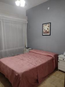 a bedroom with a bed with a pink bedspread at CASA CENTRICA con SALIDA al RIO in Mina Clavero