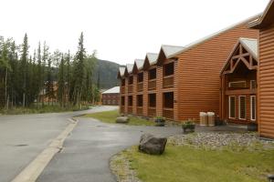 a road next to a row of wooden buildings at Denali Park Village in McKinley Park