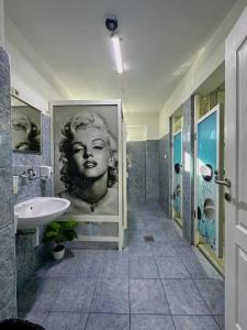 a bathroom with a sink and a picture of a woman at Hostel Herz in Banja Luka