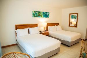 a hotel room with two beds and a mirror at Estelar Santamar Hotel & Centro De Convenciones in Santa Marta