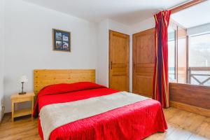 a bedroom with a red bed and a window at Lagrange Vacances Cybèle in Brides-les-Bains