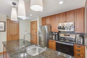a kitchen with wooden cabinets and a stainless steel refrigerator at Capitol Peak Lodge 3205 & 3207 by Snowmass Mountain Lodging in Snowmass Village +29 photos