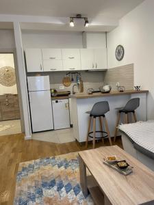 ポドゴリツァにあるApartman Starsの白いキャビネットとテーブルと椅子のあるキッチン