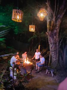 a group of people sitting around a table with a fire at River Glamping Melgar in Melgar +43 photos