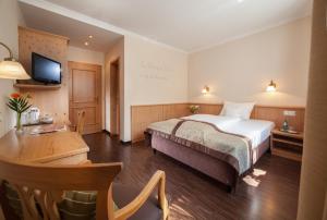 a hotel room with a bed and a desk and a television at Hotel Eschenhof in Kirchheim