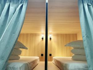 two beds in a room with blue curtains at UNPLAN Hostel in Madrid