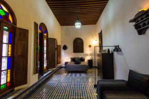 uma sala de estar com um sofá e vitrais em Dar Nejma em Fez