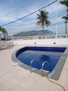 einen Pool neben einem Strand mit einer Palme in der Unterkunft Casa de praia Enseada in Guarujá