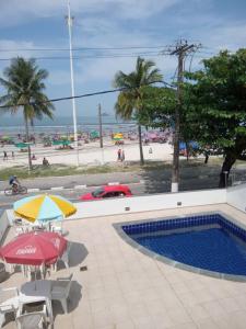 einen Pool mit Sonnenschirmen und Stühlen sowie einen Strand in der Unterkunft Casa de praia Enseada in Guarujá