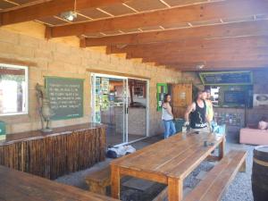 two people standing in a restaurant with a wooden table at The Wild Farm Backpackers in Wilderness