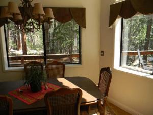Un comedor con mesa y sillas y dos ventanas. en Wawona Glade, en Wawona