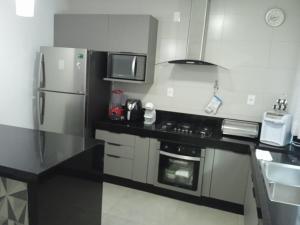 a kitchen with a refrigerator and a stove top oven at Casa Alto Padrão Parque Leste - Compartilhada in Lavras