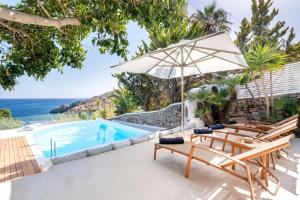 a villa with a pool and chairs and an umbrella at Zegna Pool Villa, Three Bedrooms in Mikonos