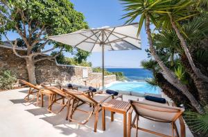 a group of chairs and an umbrella next to a swimming pool at Zegna Pool Villa, Three Bedrooms in Mikonos +51 photos