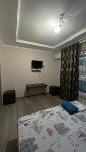 a bedroom with a bed and a tv on the wall at Three Star in Almaty