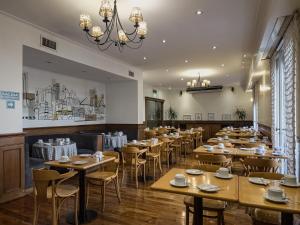 a restaurant with wooden tables and chairs and a chandelier at Hotel Marbella in Buenos Aires