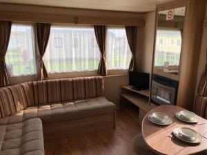 ein Wohnzimmer mit Sofa und Tisch in der Unterkunft Golden Anchor Holiday Park in Chapel Saint Leonards