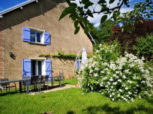 a house with a table and chairs and a bush with flowers at Chambre famille table d'hôte avec jardin à la campagne le nid qui danse vers Vesoul de 1 à 5 personnes in Baignes