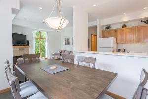 a kitchen and dining room with a wooden table and chairs at Bright and Clean, Walk Everywhere, Shared Pool and Hot Tub in Whistler