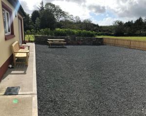 3 bedroom cottage near Kilrush & Doonbeg في غابات كيلرَش: فناء من الحصى مع طاولة نزهة ومقعد