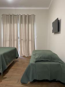 a bedroom with two beds and a television on the wall at Flat Beija-Flor - 500m da praia in Ubatuba