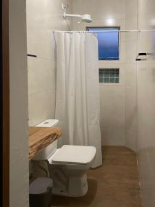 a white bathroom with a toilet and a shower at Flat Beija-Flor - 500m da praia in Ubatuba