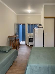a room with two beds and a refrigerator and a table at Flat Beija-Flor - 500m da praia in Ubatuba