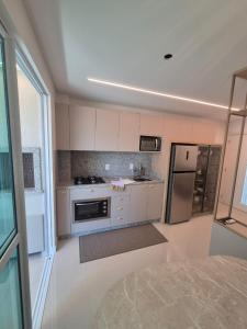 イタペマにあるApartamento NOVO em Itapemaの白いキャビネットとステンレス製の冷蔵庫を備えたキッチン